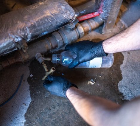 Engineer collecting a water sample during Legionella risk assessment